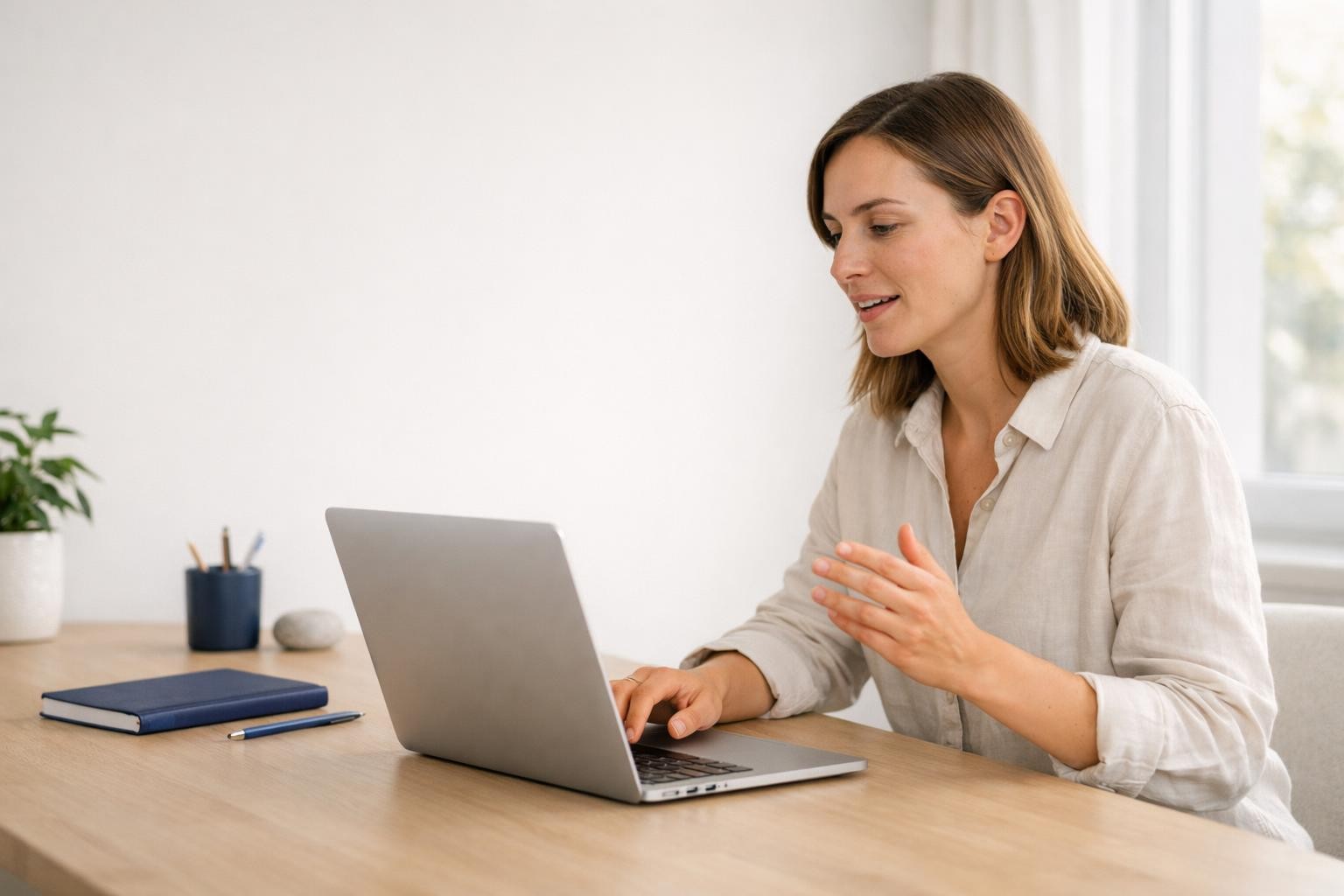 Frau diktiert konzentriert an einem Mac in einer ruhigen Arbeitsumgebung.